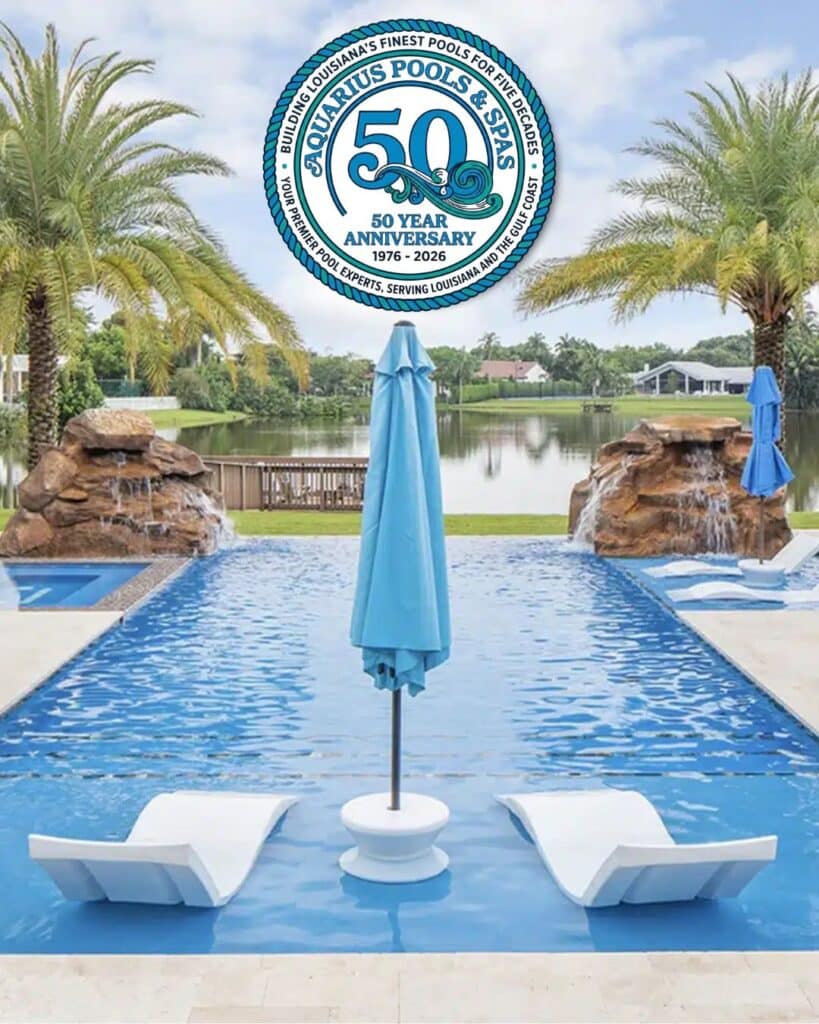 Poolside view with two white chaise lounges facing a blue pool, a blue umbrella between them, palm trees, and a 50th anniversary logo above.